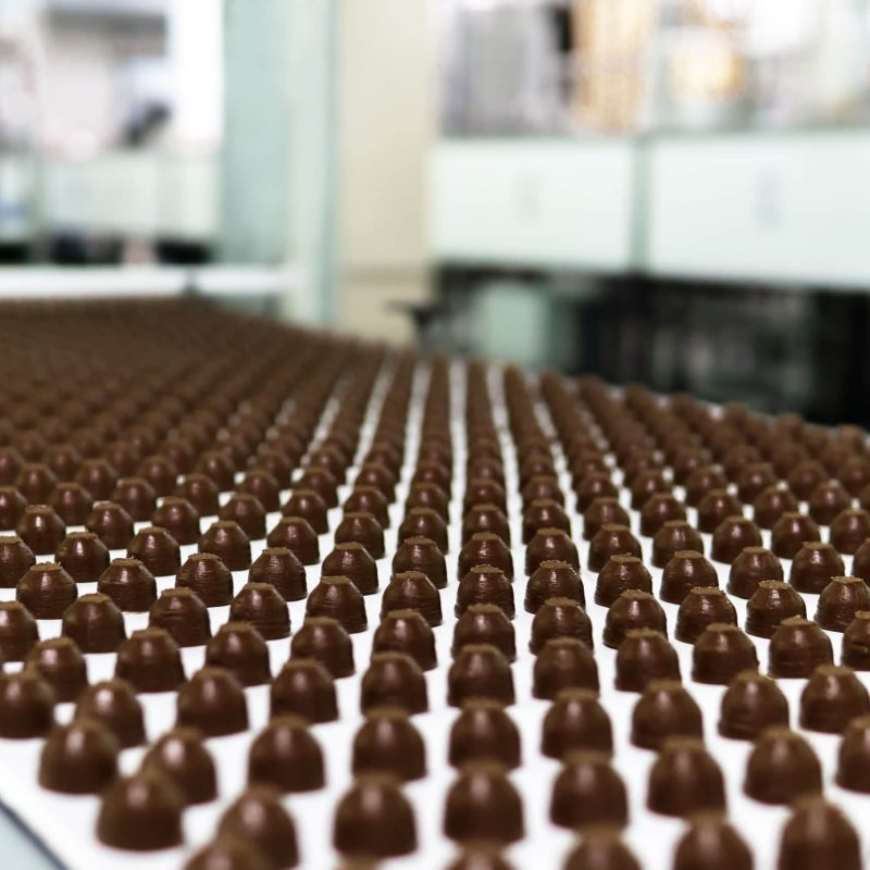 rangées de garnitures pour chocolats fabriqués à la machine, sur un convoyeur d'une chocolaterie